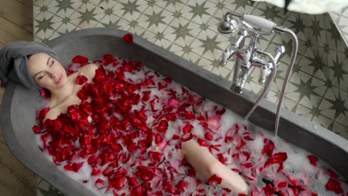 性感女孩躺在一个大石头浴缸里，手里拿着一朵玫瑰花