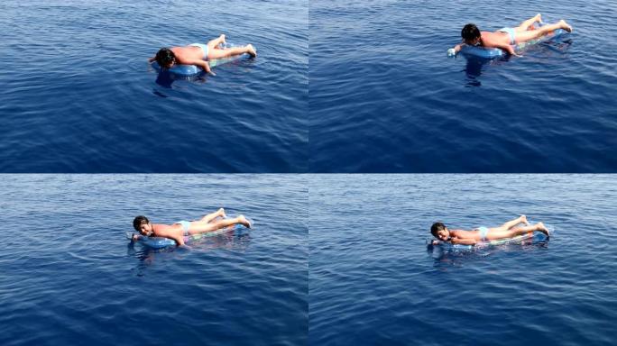 充气床垫上的少年男孩在海上玩耍