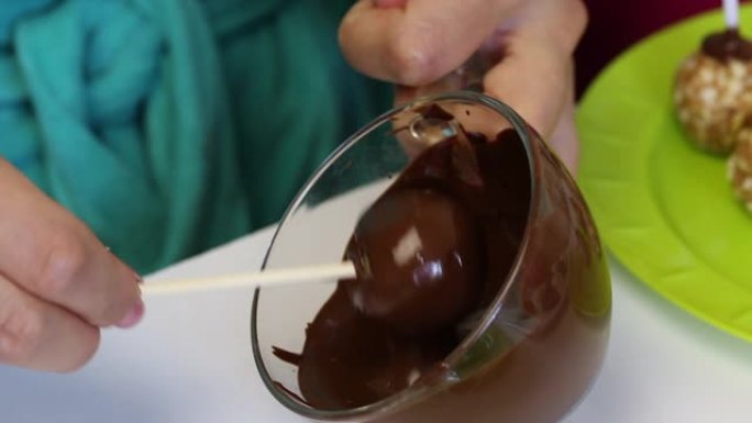 一个女人在融化的黑巧克力中蘸一个爆米花方坯。