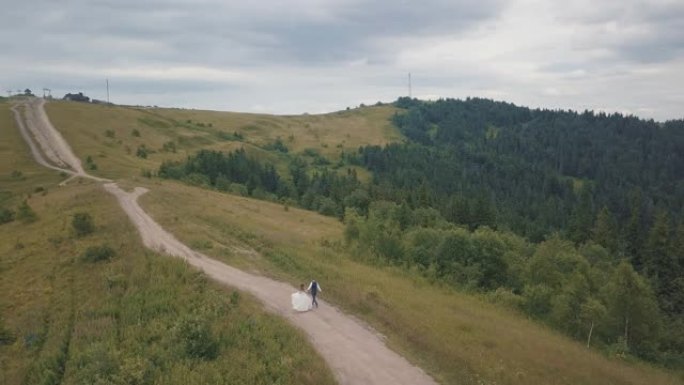 新郎和新娘在山上奔跑。空中无人机射击