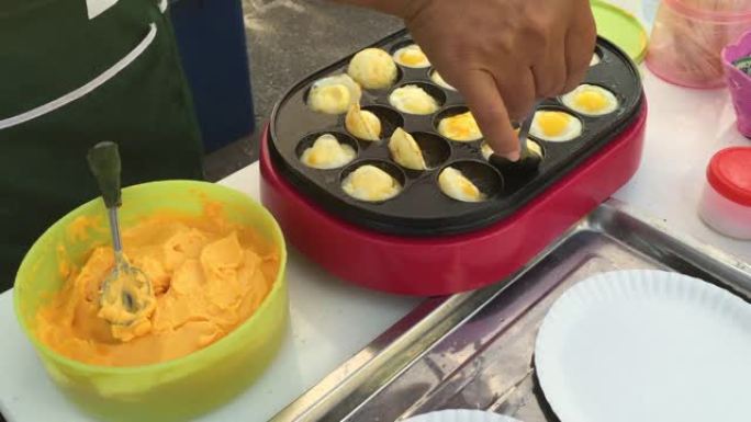 泰国街头小贩在沸腾的锅里炸薯条小鹌鹑蛋
