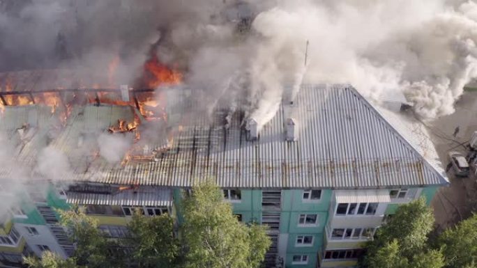 一栋住宅高层建筑的屋顶燃烧，大火冒出浓烟。顶视图