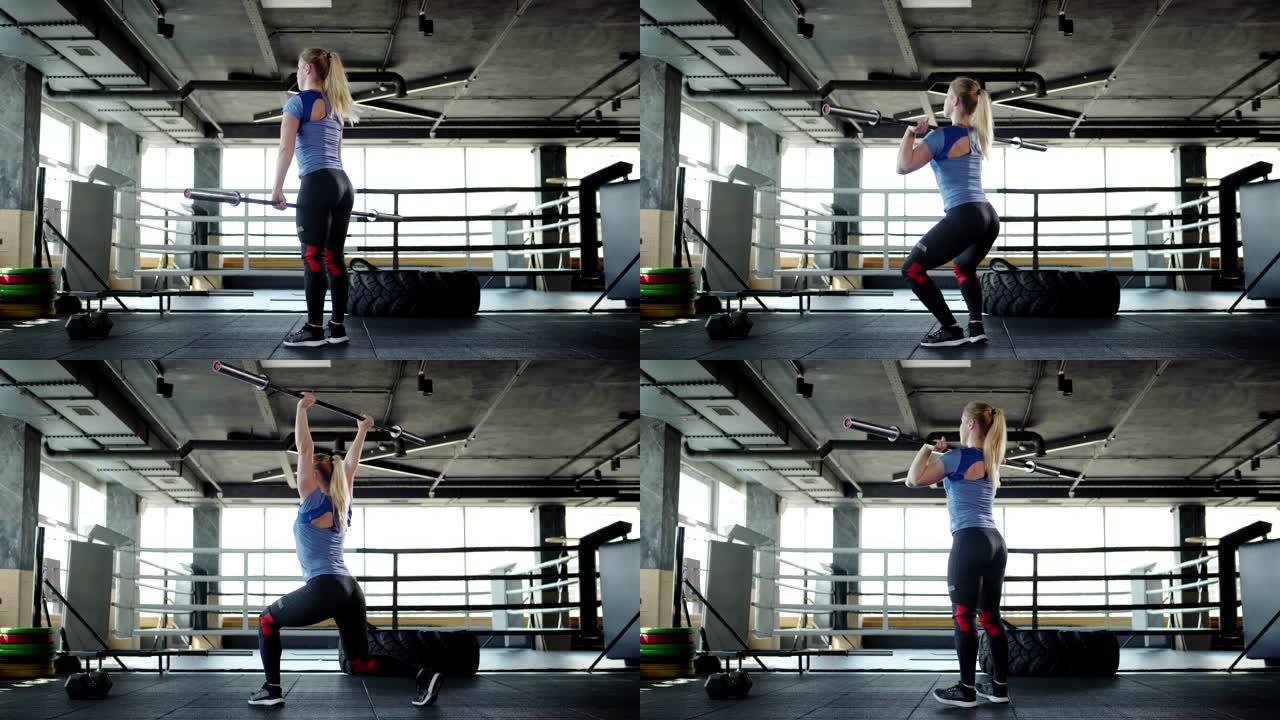金发女运动员在健身房锻炼时举起杠铃做挺举运动的四分之三后视图