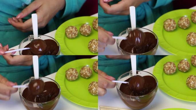 一个女人在融化的巧克力中蘸一个爆米花方坯，然后摇晃。盘子上的下一个是现成的空白。