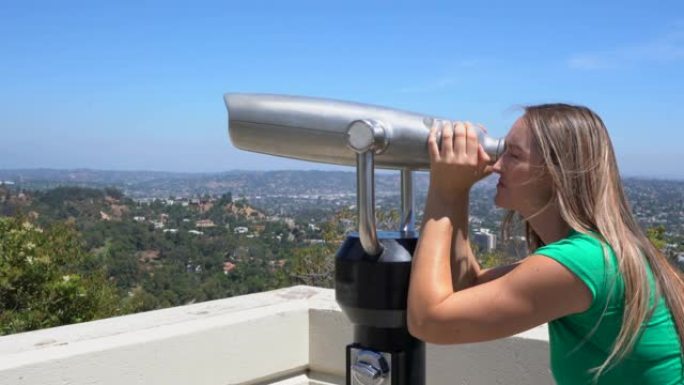 白人妇女通过双目望远镜看着城市天际线