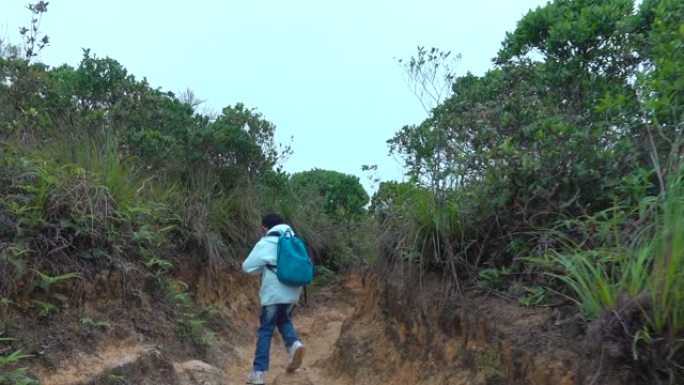 亚洲男孩沿着山路徒步旅行