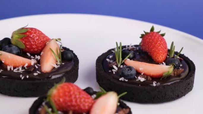 饼干外壳巧克力馅饼，蓝莓和草莓套装在蓝色背景上。