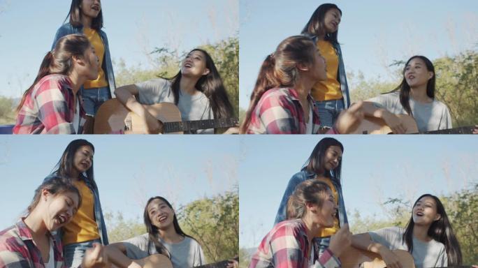 亚洲青少年组合女孩唱歌，坐在露营地弹吉他，夏天的下午