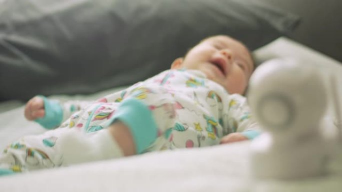 婴儿在婴儿监视器旁边的床上移动的慢动作