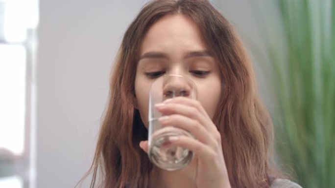 快乐的女人在浴室服用维生素胶囊和玻璃喝水