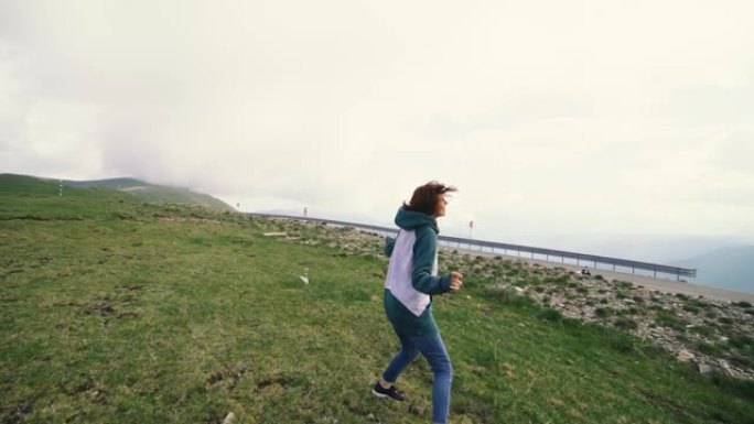 一个年轻的女徒步旅行者在山顶上奔跑和旋转。Trancalpina，罗马尼亚喀尔巴阡山脉慢动作