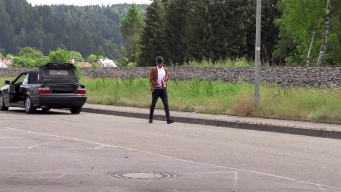 一个年轻人站在一辆破车附近
