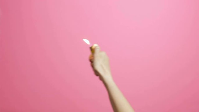 女性手打开点烟器，在粉红色的工作室背景上闪烁一闪一闪，扇灯，创意点子着火了