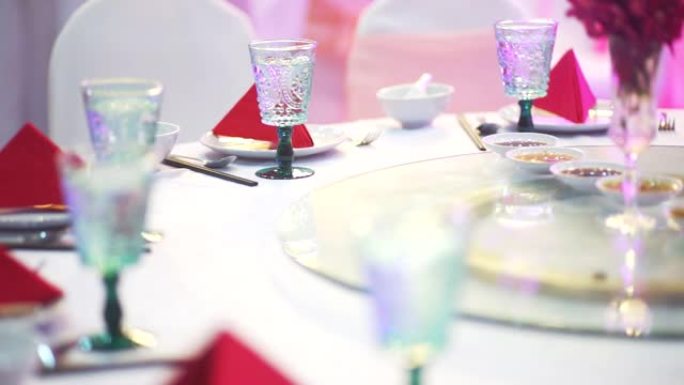 室内配有红色餐巾纸、陶器和白色桌布眼镜的豪华婚礼招待会或活动派对圆桌会议。