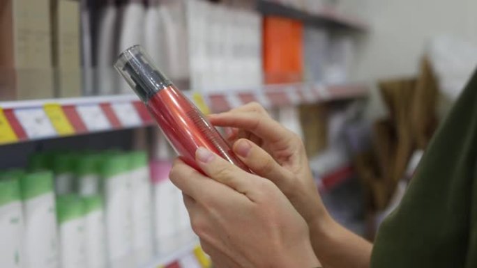 A young woman chooses hair oil or balm. She reads 