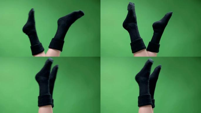 特写镜头，拍摄可爱的黑色短针织袜子中的女性青少年腿，嬉戏地移动，背景孤立在绿色上