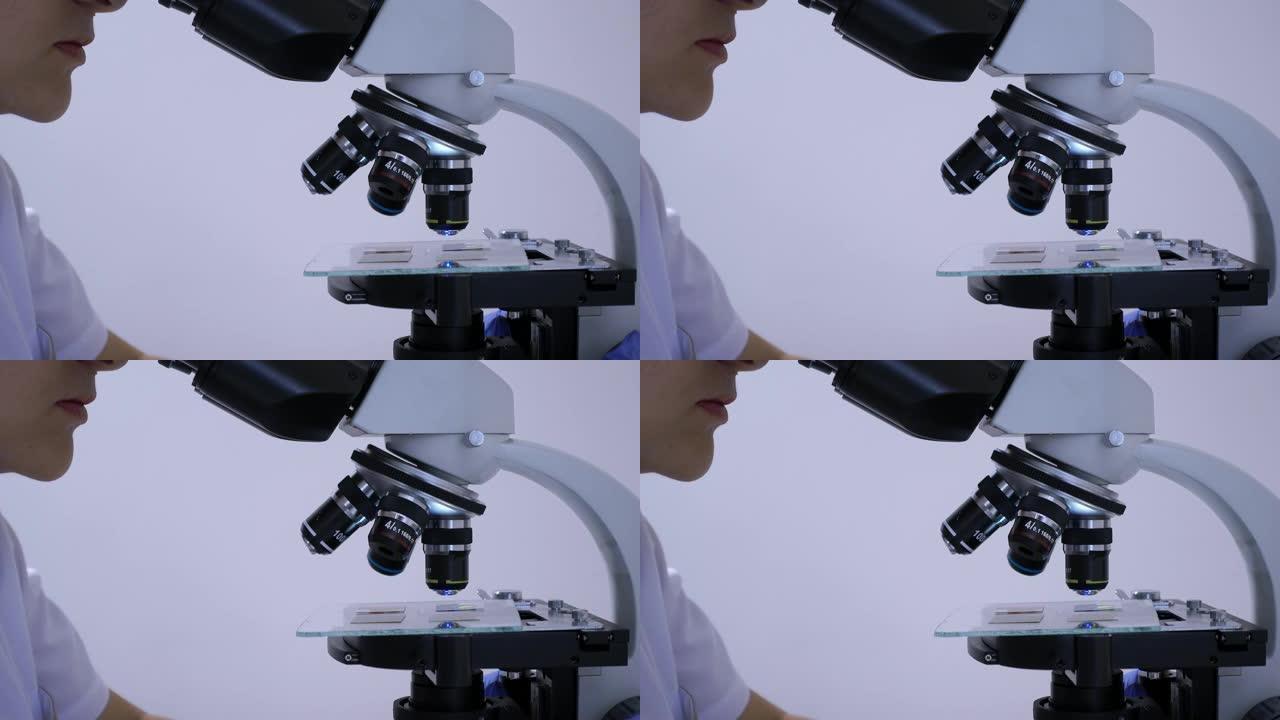 女实验室技术员凝视着显微镜的目镜