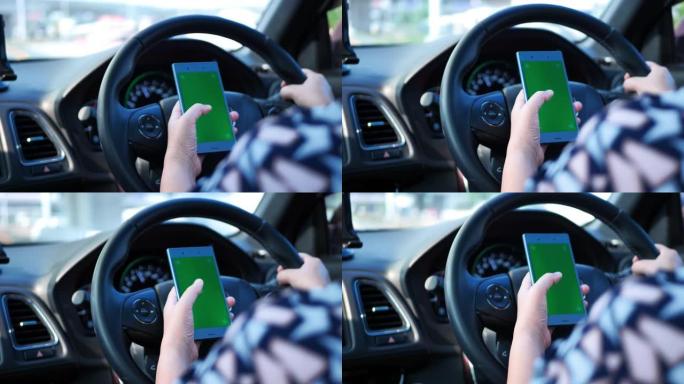女人在路上开车，使用绿屏智能手机。看地图或听音乐。