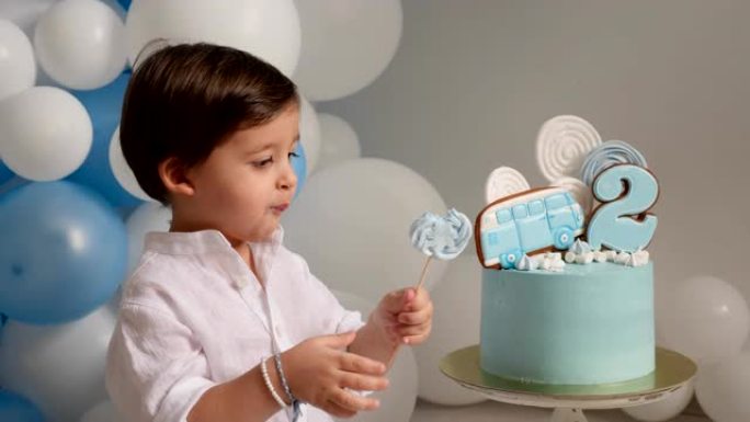 两岁的男孩用汽车吃节日的蓝色蛋糕