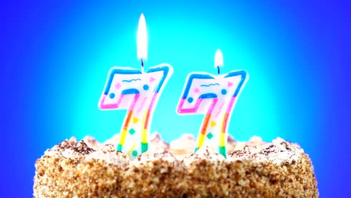 带有燃烧的生日蜡烛的生日蛋糕。77号。背景改变颜色