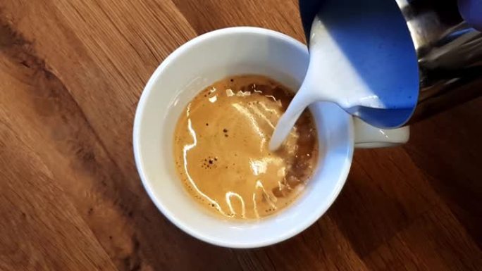 将发泡的素食燕麦牛奶倒入一杯意式浓缩咖啡中，用于卡布奇诺或拿铁玛奇朵