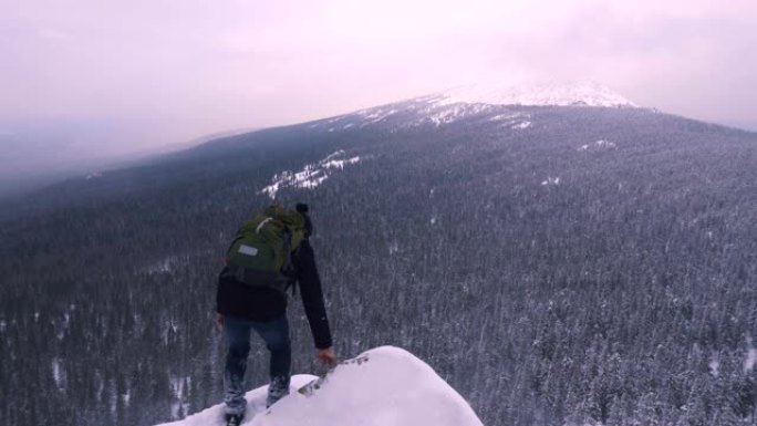 一个年轻人，一个游客，站在白雪皑皑的山边，敬佩山顶。