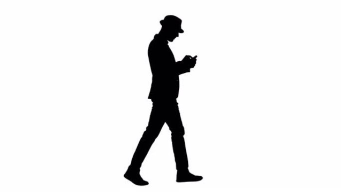 剪影严肃的阿拉伯休闲男子走路时使用智能手机