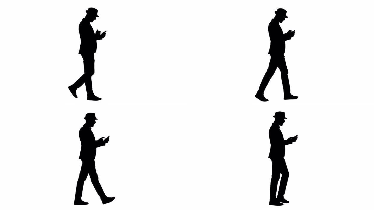 剪影严肃的阿拉伯休闲男子走路时使用智能手机
