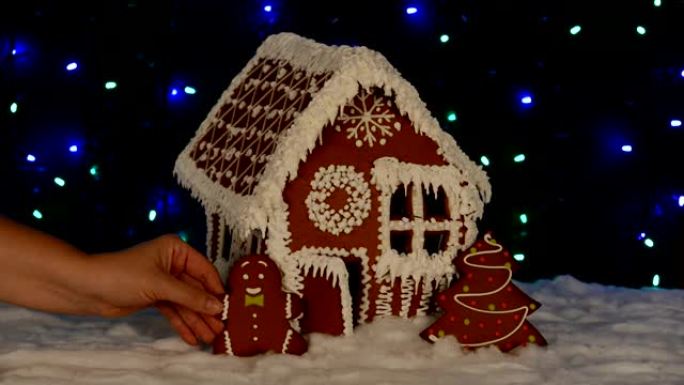 手工制作的可食用姜饼屋，小矮人手工添加，新年树，雪装饰，花环背景照明