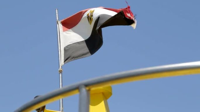 埃及国旗在蓝天下随风飘扬。