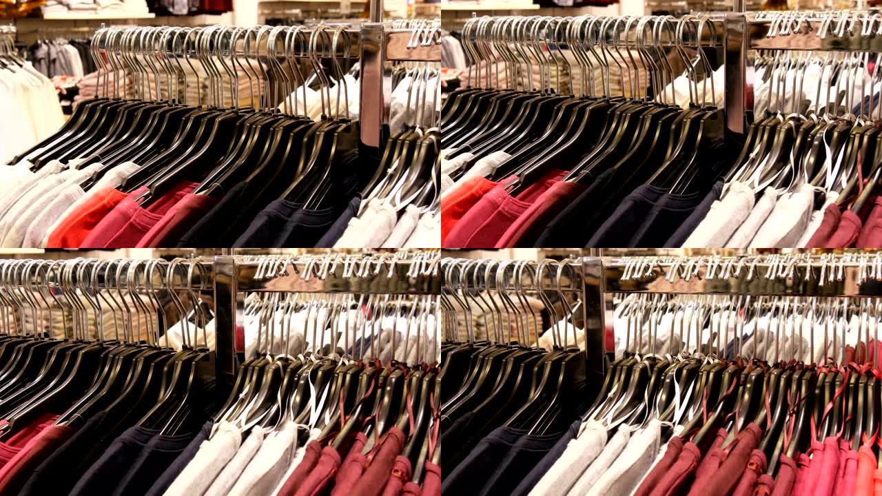 购物中心或购物中心的服装店中，大量不同颜色的女装挂在衣架上，并躺在货架上