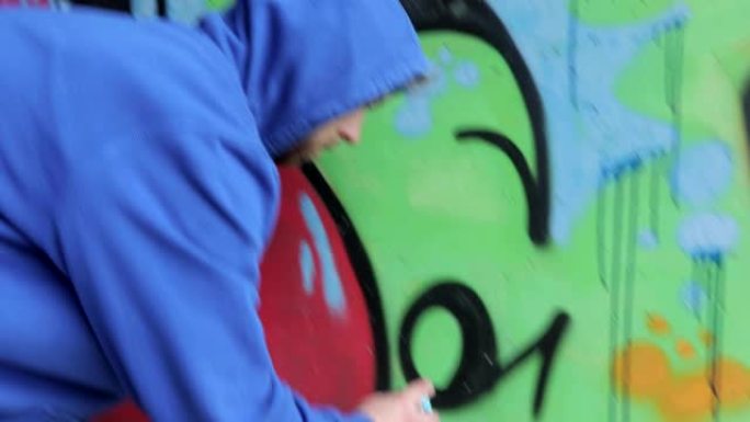 年轻的成人涂鸦艺术家在乡村地区的隧道中绘画