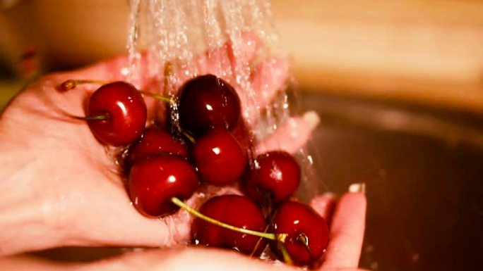 樱桃。女人的手在水压下洗樱桃。
