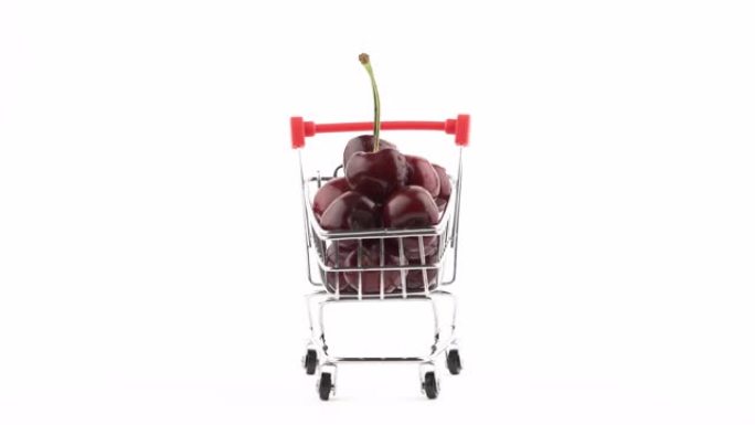 迷你玩具手推车中的樱桃水果。旋转桌子上的浆果。特写，孤立，在白色背景上。新鲜和