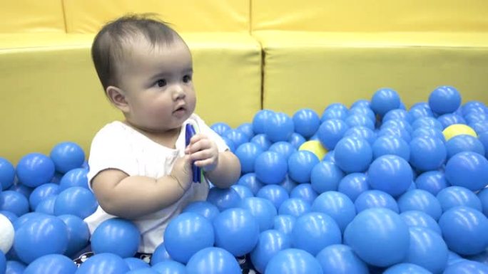 亚洲女婴用蓝色球在干燥的水池里玩方形磁铁
