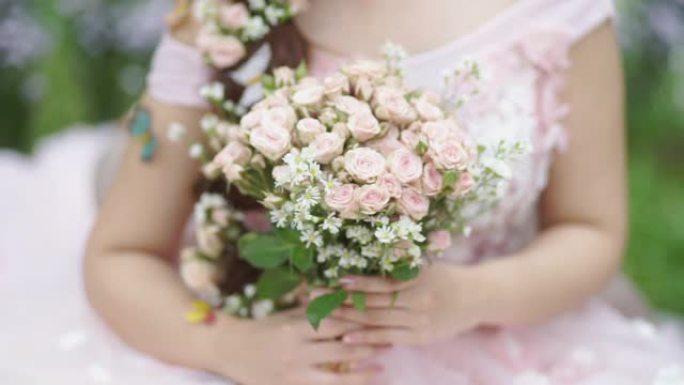美丽的新娘在户外双手捧着一束花。