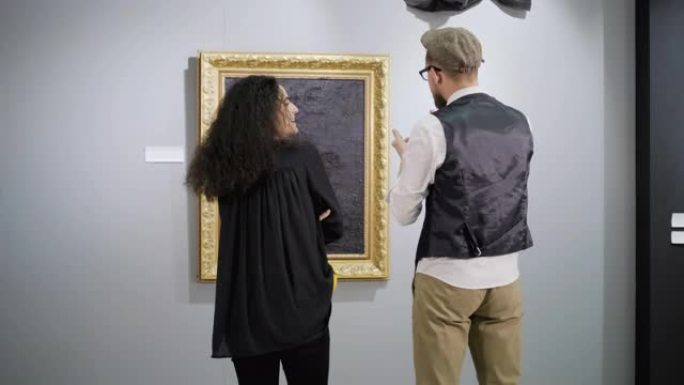 一对现代艺术展览的参观者在图片前聊天