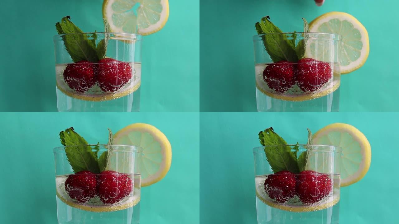 桌子上是一杯矿泉水。在水中放一片柠檬，草莓和新鲜的薄荷叶。可见美丽的气泡游戏。一个女人把柠檬片放在玻