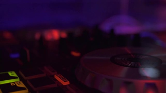 DJ音响控制台，用于在迪斯科俱乐部的夜间派对上与彩色灯光混合音乐。迪斯科派对的特写DJ混音器和音乐控