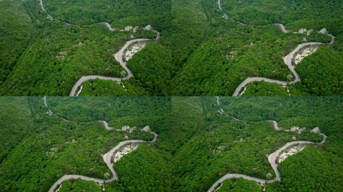 带有汽车和卡车的山蜿蜒道路的鸟瞰图。