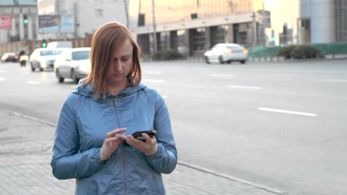 一名中年妇女正在人行道上行走，在智能手机中阅读消息。