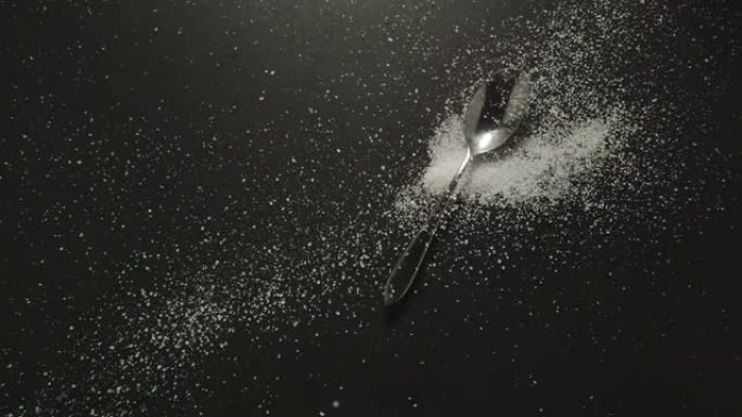 慢动作: 勺子上的糖粒掉落在黑色桌子上