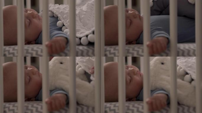 慈爱的母亲把玩具放在她熟睡的孩子附近的特写镜头。可爱的婴儿男婴睡在他的婴儿床。
