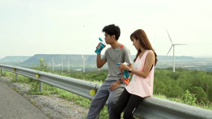 体育情侣一起跑步亚洲情侣坐着累了喝水