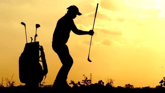剪影男高尔夫球手在太阳落山的外面练习