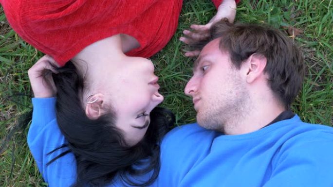 恋爱中的浪漫情侣看着彼此躺在草地上的眼睛