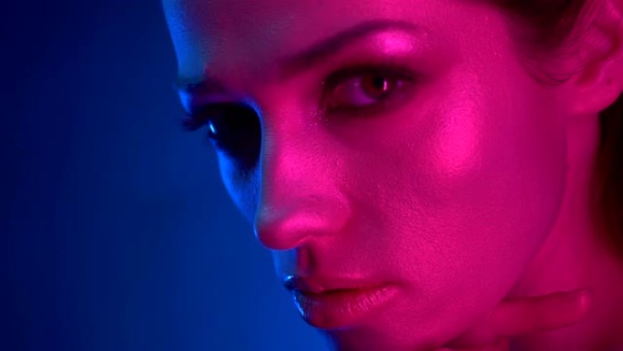 特写幻灯拍摄的模特，在蓝色和粉红色的霓虹灯集中在相机碰触她的肩膀。
