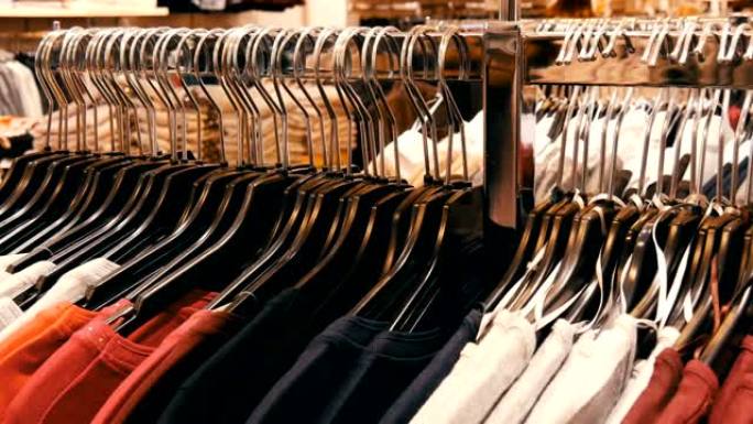 购物中心或购物中心的服装店中，大量不同颜色的女装挂在衣架上，并躺在货架上