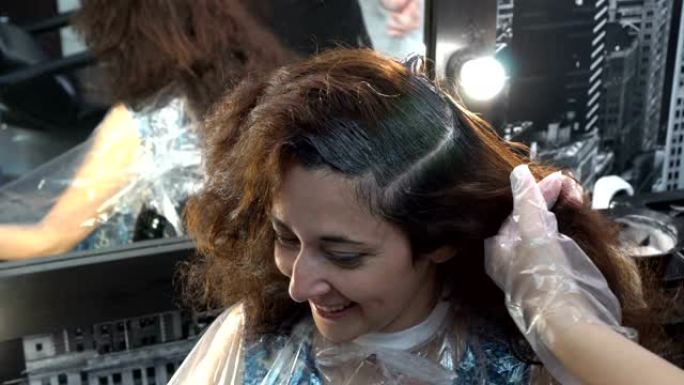 女孩的头发是在理发店染的。理发师用油漆刷涂在她的头发上。特写。4K。