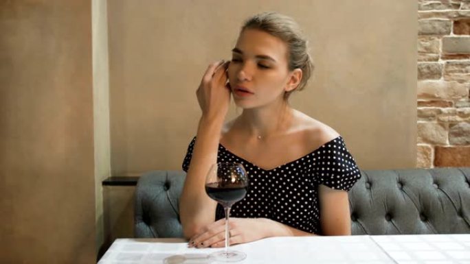 一位年轻女子的肖像穿着晚礼服，在餐厅里喝着一杯酒